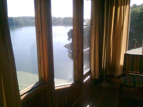a room with two windows with a view of a lake at Cabañas Quillay Viejo in Lago Rapel