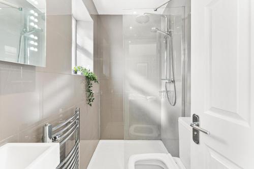 a white bathroom with a shower and a toilet at The Augustine - Stylish City Centre Gem in Kent