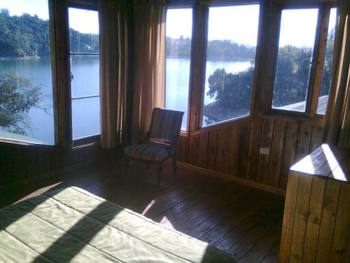 a room with windows and a chair with a view of a lake at Cabañas Quillay Viejo in Lago Rapel