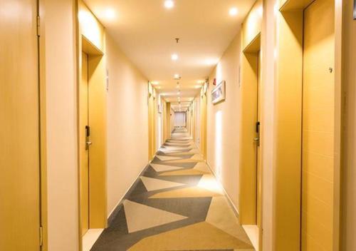 a hallway with yellow walls and a long hallway with black and white floors at City Comfort Inn Changchun Jida First Hospital Xi Minzhu Street in Changchun