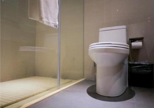 a bathroom with a toilet and a glass shower at City Comfort Inn Yichang Yiling Bus Station Wanda Plaza in Baiyang