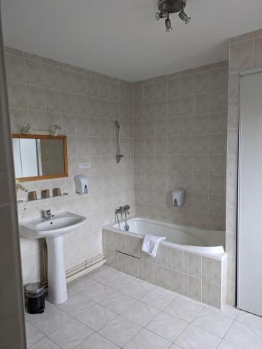 une salle de bain avec un lavabo et une baignoire dans l'établissement Hôtel Le Millésime, à Meymac