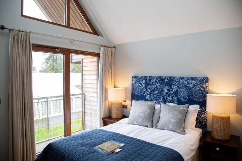 a bedroom with a bed and a large window at Crocus Northbrook Park Chalet in Farnham