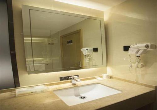 een badkamer met een wastafel en een grote spiegel bij City Comfort Inn Luchuan Hot Spring Plaza High-speed Railway Station 