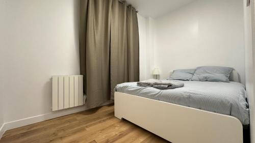 a white bedroom with a bed and a window at Lacharriere-Logement entier 38m2 in Paris