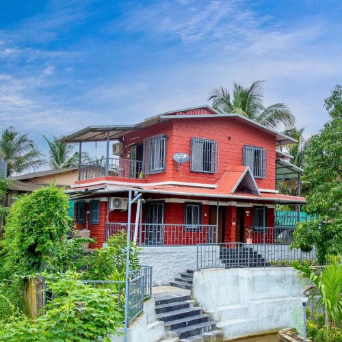 a red house with stairs in front of it at Riyansh Alibaug Villas and Resort in Alibaug
