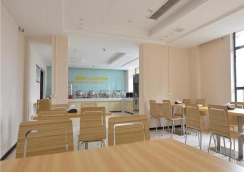 a room with chairs and tables and a kitchen at City Comfort Inn Huanggang Qichun Exhibition Center in Qichun