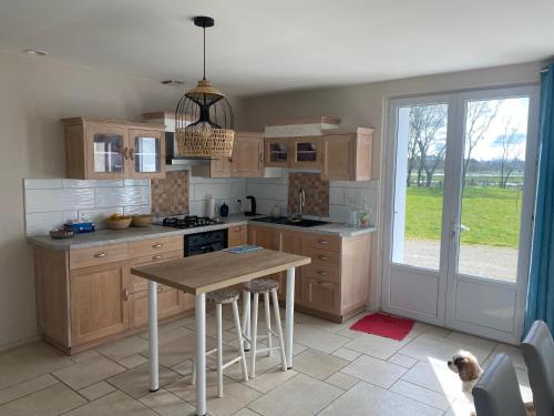 une cuisine avec des placards en bois et une table avec un chien dans l'établissement Maison 3ch soullans, à Soullans