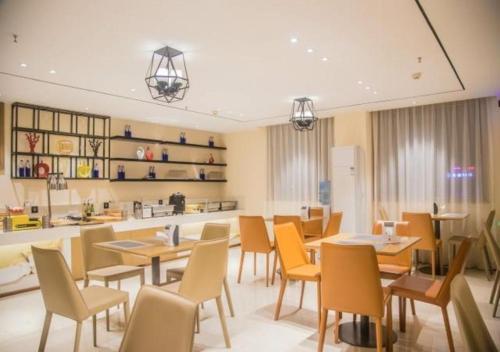 a dining room with tables and chairs and a kitchen at City Comfort Inn Wuzhou Municipal Government Vocational College in Wuzhou