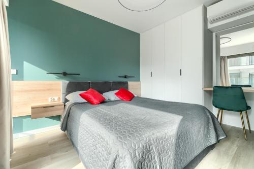a bedroom with a bed with red pillows on it at Apartamenty Solaris in Darłówko