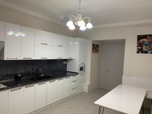 a kitchen with white cabinets and a black counter top at Cultural Crossing Hotel in Tbilisi City