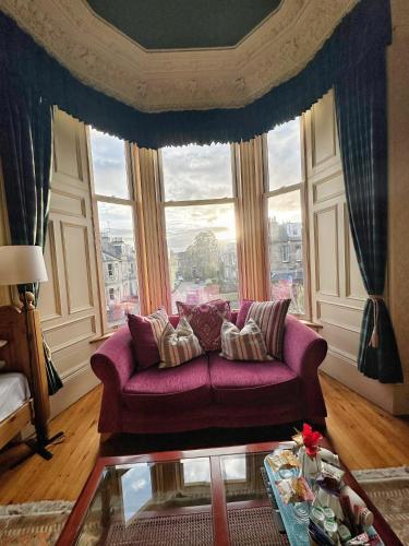 a living room with a purple couch in front of a window at Rosehall Hotel in Edinburgh