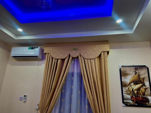 a room with a blue ceiling and a curtain at Enugu Airbnb / shortlet Serviced Apartment in Enugu