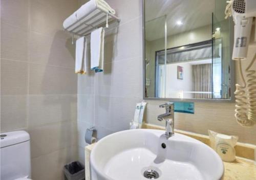 a bathroom with a sink and a mirror and a toilet at City Comfort Inn Liuzhou Baisha Bus Station Shengli Barbecue City in Liuzhou