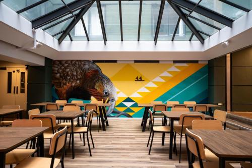 a restaurant with tables and a mural of a peacock at Haka House Wellington in Wellington