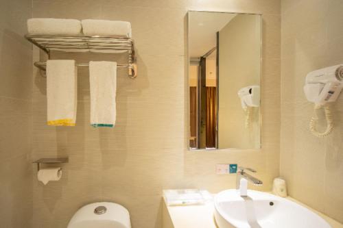 La salle de bains est pourvue d'un lavabo, de toilettes et d'un miroir. dans l'établissement City Comfort Inn Maoming High Speed Railway Station, à Maoming