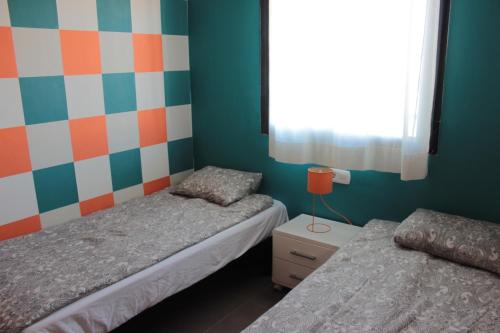 um quarto com 2 camas e uma parede colorida em M515 Apartamento Las Dunas Oliva Nova em Oliva