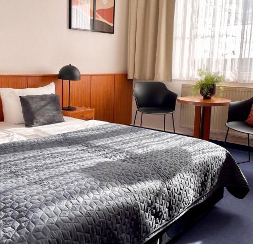 a bedroom with a bed with two chairs and a table at Garni Hotel Gartenstadt Erfurt in Erfurt