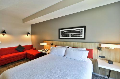 a hotel room with a bed and a red couch at Hilton Garden Inn Savannah Historic District in Savannah