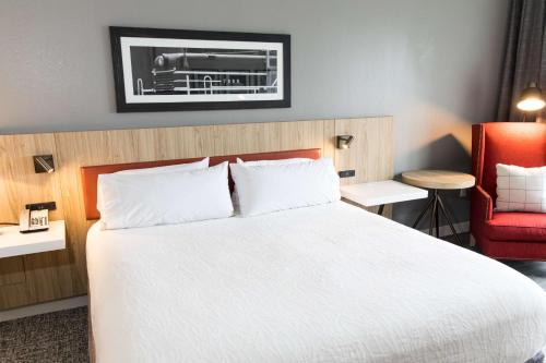 a hotel room with a bed and a red chair at Hilton Garden Inn Savannah Historic District in Savannah