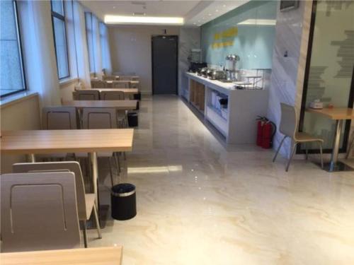 QilitangzhenにあるCity Comfort Inn Hefei Shuanggang Fuyang Roadのテーブルと椅子のあるレストラン、キッチンが備わります。