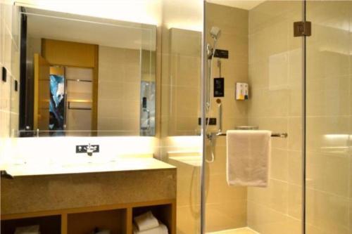 W łazience znajduje się prysznic, umywalka i lustro. w obiekcie City Comfort Inn Jinan Railway Station Daming Lake w mieście Jinan