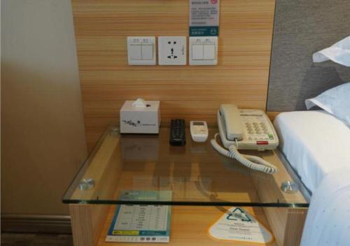 um quarto com uma cama e um telefone numa mesa de vidro em City Comfort Inn Ji'an Railway Station Jinggangshan University 
