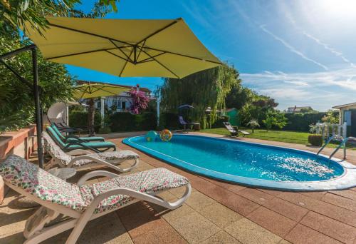 uma piscina com duas cadeiras e um guarda-sol em Villa Sikovo em Sveti Filip i Jakov