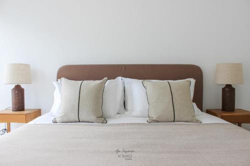 貝雅的住宿－Nomad Houses - Ap Tereno，一间卧室配有一张带白色枕头的床和两盏灯。
