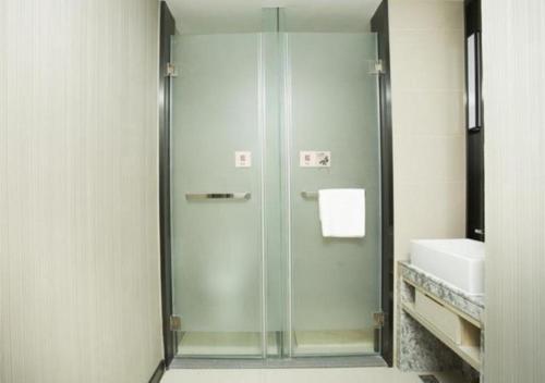 W łazience znajduje się szklana kabina prysznicowa i umywalka. w obiekcie Echarm Hotel Changchun Jiutai District Government Railway Station 