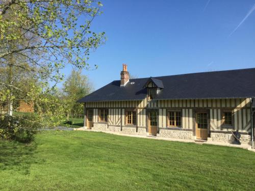 a house with a black roof and a green yard at L'auberge du Mont in Le Breuil-en-Auge