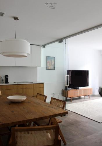 a dining room with a wooden table and a television at Nomad Houses - Ap Tereno in Beja