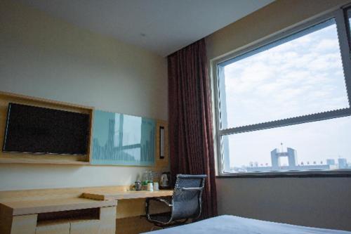 a bedroom with a desk and a large window at City Comfort Inn Ganzhou Railway Station in Ganzhou