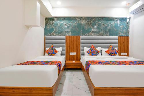 two beds in a room with white walls at FabHotel Amantra in Ahmedabad