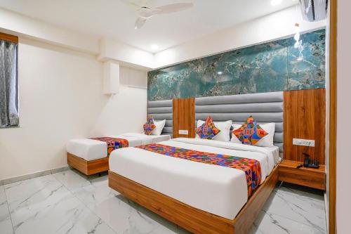 a bedroom with two beds and a painting on the wall at FabHotel Amantra in Ahmedabad