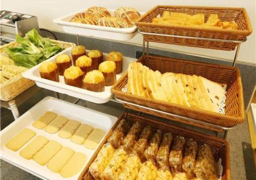 a buffet with trays of food and pastries on a counter at City Comfort Inn Liuzhou Gubu Street Ma'anshan Park in Liuzhou