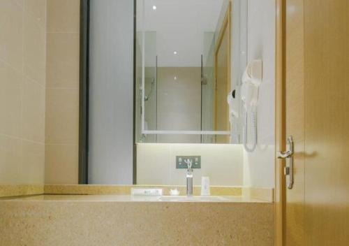 ein Badezimmer mit einem Waschbecken und einem großen Spiegel in der Unterkunft City Comfort Inn Liuzhou Gubu Street Ma'anshan Park in Liuzhou