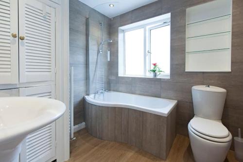 een badkamer met een bad, een toilet en een raam bij Central - Family House in Harrogate