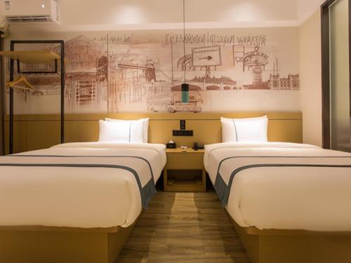 2 Betten in einem Zimmer mit Wandzeichnung in der Unterkunft City Comfort Inn Baise High Speed Railway Station in Baise