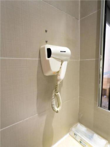 a hair dryer on the wall of a bathroom at City Comfort Inn Foshan Longjiang Exhibition Center in Shunde