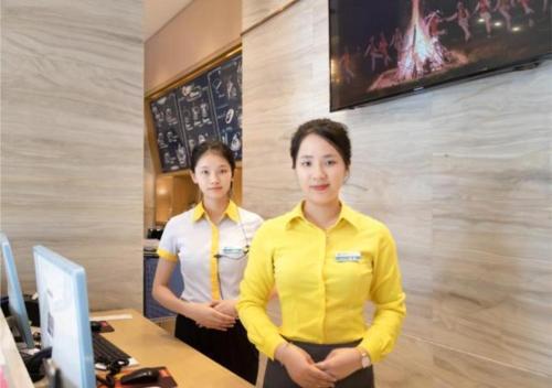 dos mujeres de pie en una oficina con los brazos cruzados en City Comfort Inn Wuzhou Teng County Bus Station, en Tengcheng
