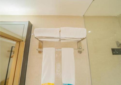 ein Badezimmer mit zwei weißen Handtüchern auf einem Duschvorhang in der Unterkunft City Comfort Inn Wuzhou Teng County Bus Station in Tengcheng
