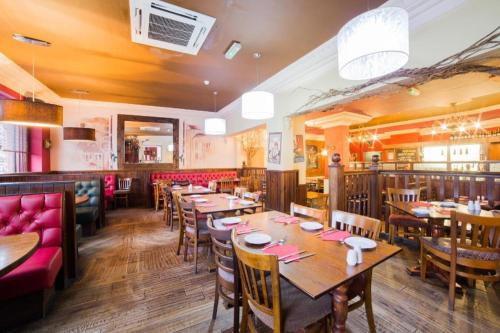 - un restaurant avec des tables et des chaises en bois dans une chambre dans l'établissement OYO Hotel Majestic, à Lockerbie