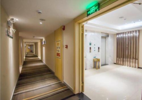 an empty hallway in a building with a green exit sign at City Comfort Inn Yichang Dongshan Three Gorges University Shuiyuecheng in Yichang