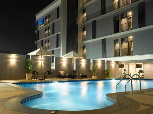 Ban Chak Samo的住宿－B2 Amata Nakorn Premier Hotel，一座游泳池,在晚上在建筑物前