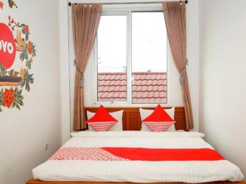 a bed with red pillows in a room with a window at Hotel Meigah in Tanjungpandan