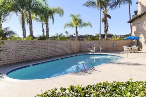 a swimming pool with two chairs next to a brick wall at Rodeway Inn Carlsbad in Carlsbad