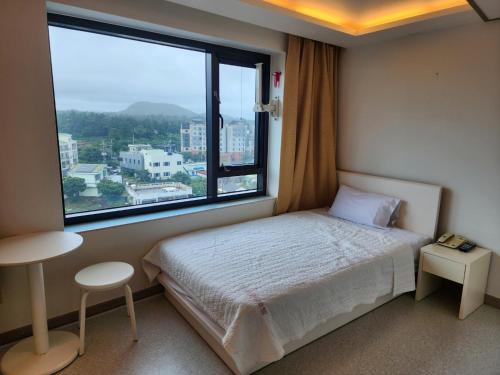 sypialnia z łóżkiem i dużym oknem w obiekcie Rezion Hotel w mieście Seogwipo