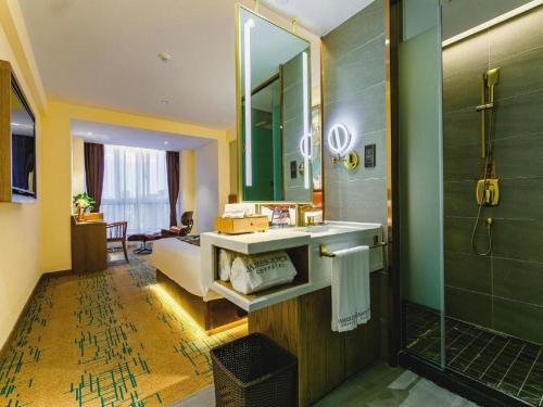 uma casa de banho com um lavatório, um espelho e um chuveiro em James Joyce Coffetel· Xianyang Renmin Road Central Square Store em Xianyang