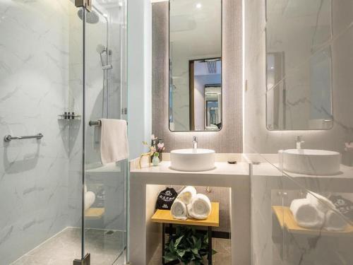 W łazience znajdują się 2 umywalki i przeszklony prysznic. w obiekcie Magnotel Tongxiang Shimao Center w mieście Tongxiang